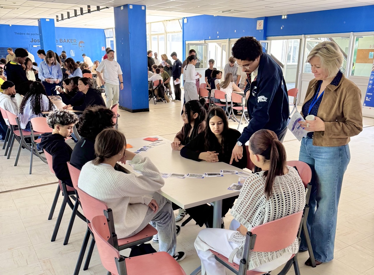 Des collégiennes et collégiens réunis autour de tables disposent des cartes, accompagnés par les étudiants qui animent l’atelier.